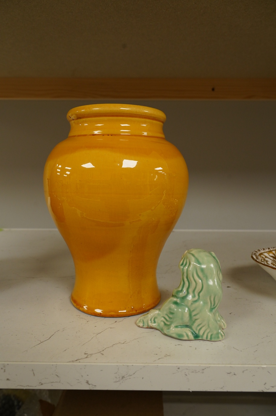 A Brannam yellow vase with stylised decoration of a standing owl with a background of the moon, clouds and three stars, 21cm high, and a Brannam, Barnstaple, a shade of green stylised sitting Dog of Fo, 7.5cm high. Condi